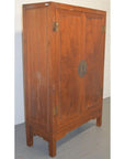 Brown lacquered wood Chinese cabinet with two doors, brass hinges, and round metal plate on the center front.