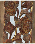 Close-up of an antique carved wooden panel with gold and red floral designs and a bird among ornate leaves.