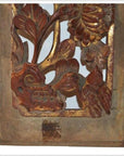 Close-up of a brown wooden panel with floral carvings and gold accents in a rectangular frame.
