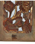Close-up of a brown wooden panel with floral carvings and gold accents in a rectangular frame.