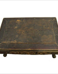 Rectangular antique Indonesian wood table with ornate gold carvings and four short hand-carved legs, close-up view.