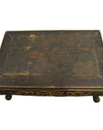 Rectangular antique Indonesian wood table with ornate gold carvings and four short hand-carved legs, close-up view.