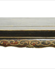 Close-up of antique Indonesian carved wood table edge with ornate hand-carved and painted decorative patterns.
