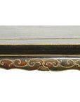 Close-up of antique Indonesian carved wood table edge with ornate hand-carved and painted decorative patterns.