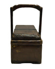 Brown wooden antique Chinese dowry box with tall rectangular handle and hinged lid, close-up.