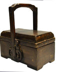 Dark wood Chinese dowry box with ornate carvings and metal handle, close-up on polished finish.