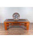 Brown Chinese elm coffee table with square legs and rattan inset top, set against a white brick wall.