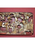 Close-up of gold and red hand-carved wood Chinese antique carving with three figures on temple wall.