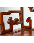 Close-up of brown wood armrest with ornate carving and natural patina on an antique Chinese chair.