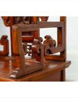 Close-up of brown wood hand-carved chair with scrollwork and natural patina, antique style.