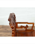 Close-up of natural wood antique Chinese chair with hand-carved details on backrest and armrest.