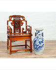 Brown wood hand-carved Chinese chair with natural patina on wooden floor next to large ceramic vase indoors.