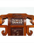 Brown wood hand-carved chair with ornate scrolls and intricate patterns, natural patina, indoors.