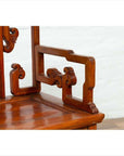 Close-up of brown wood chair with hand-carved intricate patterns and natural patina finish.
