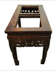 Dark wood hand carved Chinese console table with ornate legs and two rectangular open sections on tabletop, indoors.