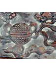 Close-up of antique Chinese red lacquered rosewood plaque with hand-carved ball, clouds, and mythical creature motifs.