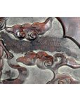 Close-up of red lacquered rosewood wall plaque with hand-carved swirling cloud designs.