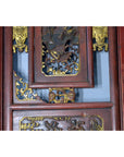 Close-up of gold-accented hand carved wood wall decor with intricate designs on a lacquered surface.