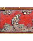 Red and gold lacquer box with floral inlay and a figure near plants, shown against a plain background.