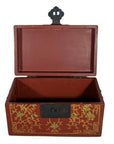 Red lacquer box with gold floral inlay, ornate black latch, on a plain surface.