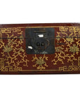 Close-up of red and gold Chinese lacquer box with raised scene on lid and large black metal front latch.