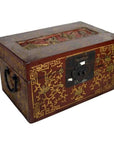 Red and gold Chinese lacquer box with raised top scene, metal handles, and ornate front lock, close-up view.