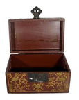 Red and gold lacquered box with raised scene on top, ornate floral patterns on front and sides, photographed indoors.