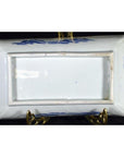 White and blue porcelain tray with landscape, pavilion, willow trees on brass stand, black background, close-up.