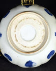 White ceramic scalloped dish with blue accents, featuring a crouching mouse and barrel cartouche, close-up view.