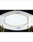 Blue and white ceramic boat-shaped dish with misty landscape and two birds, ornate brass stand, close-up.