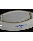 Close-up of blue and white porcelain boat-shaped dish with hand-painted mark and rectangular foot rim.