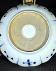 Close-up of the white porcelain Antique Fluted Plate – Wind-Swept Pine underside on an ornate gold stand.