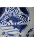 Blue and white porcelain dish with foliate hill motif and rustic brushwork, antique Asian style, close-up.