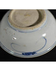 Close-up of blue and white porcelain dish base with foliate motif and rustic unglazed textured bottom.