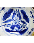 Blue and white porcelain dish with antique botanical spray pattern, radial layout, close-up top view.