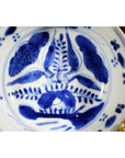 Blue and white porcelain dish with antique botanical spray pattern, radial layout, close-up top view.