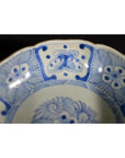 Close-up of blue and white porcelain Chinese bowl with butterfly cartouches, petal rim, floral and geometric patterns.