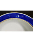 Close-up of blue and white ceramic Asian deep plate rim, showing small marks and a white spot on the glaze.