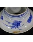 Blue and white ceramic deep plate with broad rim, minimal center, and small brown stain near bottom edge.