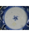 Blue and white porcelain dish with rosette medallion, blue floral pattern, and central blue emblem, close-up.