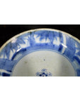 Blue and white porcelain dish with a rosette medallion and alternating patterned panels, close-up.