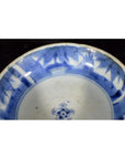 Blue and white porcelain dish with rosette medallion, alternating floral and geometric panels, close-up view.