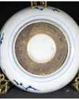 White and blue porcelain dish with rosette medallion and alternating panels, brown foot ring, on brass stand.