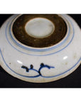 White porcelain dish with rosette medallion and alternating panels, shown upside down on a black background.