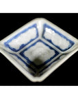 Close-up of antique blue ceramic bowl with embossed blossom detail, blue-washed corners, set on black surface.