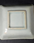 Blue and white ceramic bowl with embossed blossom design, close-up on blue-washed corners, on modern table.