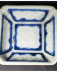 Blue-washed ceramic bowl with embossed blossom design on sides and center, close-up view.