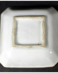 Close-up of the underside of an antique blue and white ceramic dish with chrysanthemum bloom, geometric frame, unglazed foot.