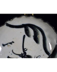 Close-up of white porcelain plate with antique ink-style bamboo branches and calligraphic brushwork.