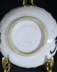 White porcelain plate with black ink-style bamboo design, displayed on an ornate gold stand, close-up view.